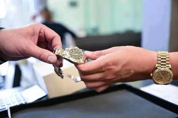 Two people buying and selling a gold rolex watch in an office setting